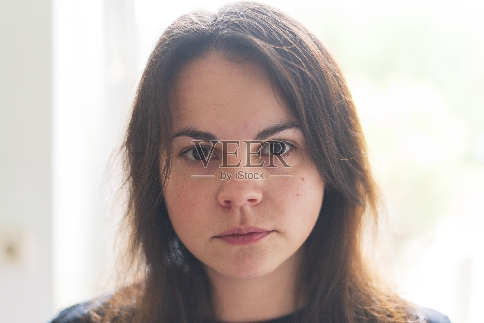 可怜的可爱女孩站在明亮窗户的背景前照片摄影图片