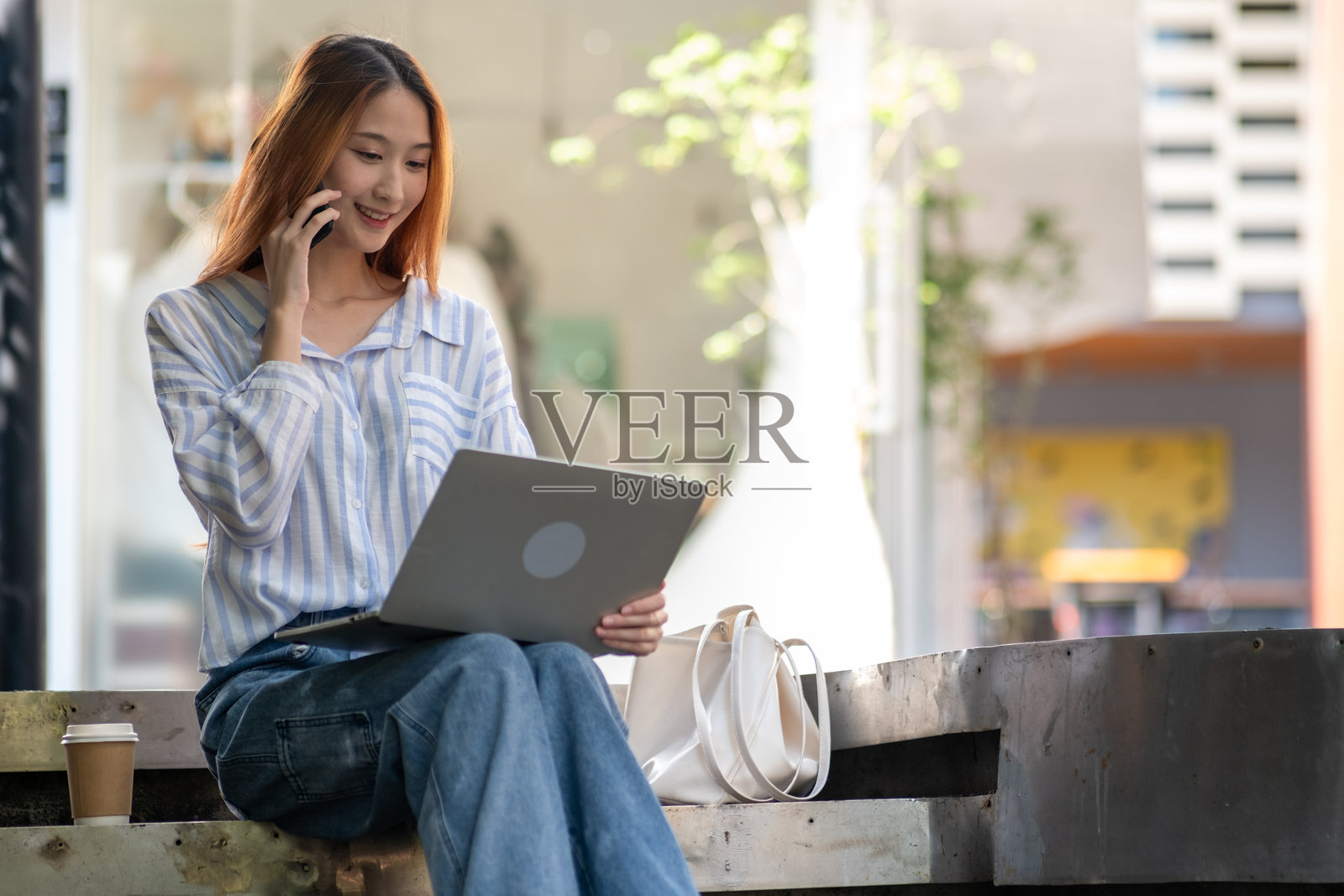 女人坐在长椅上，正在用手机通话照片摄影图片