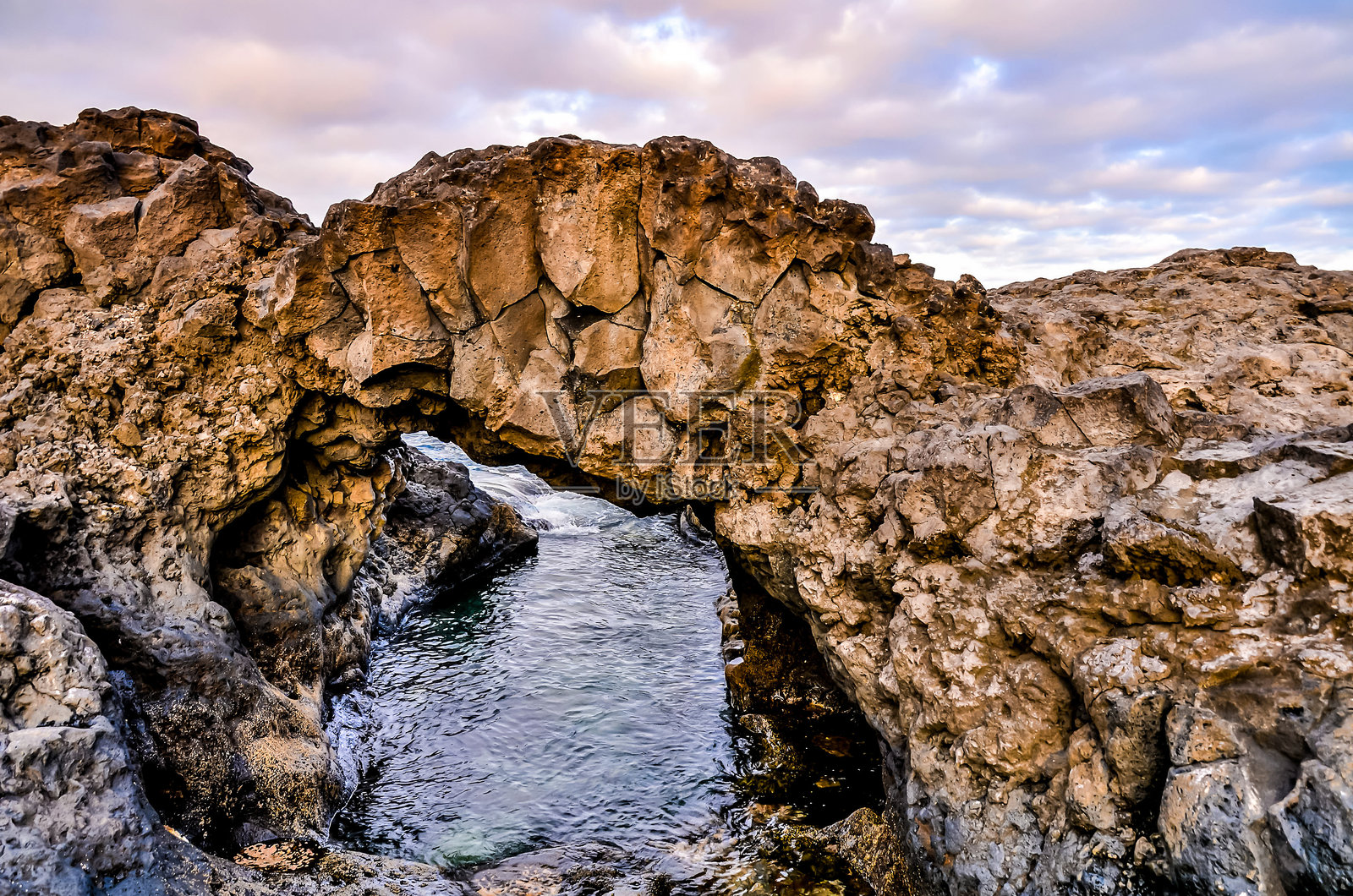 一座岩石拱门，下面流淌着一条小溪照片摄影图片