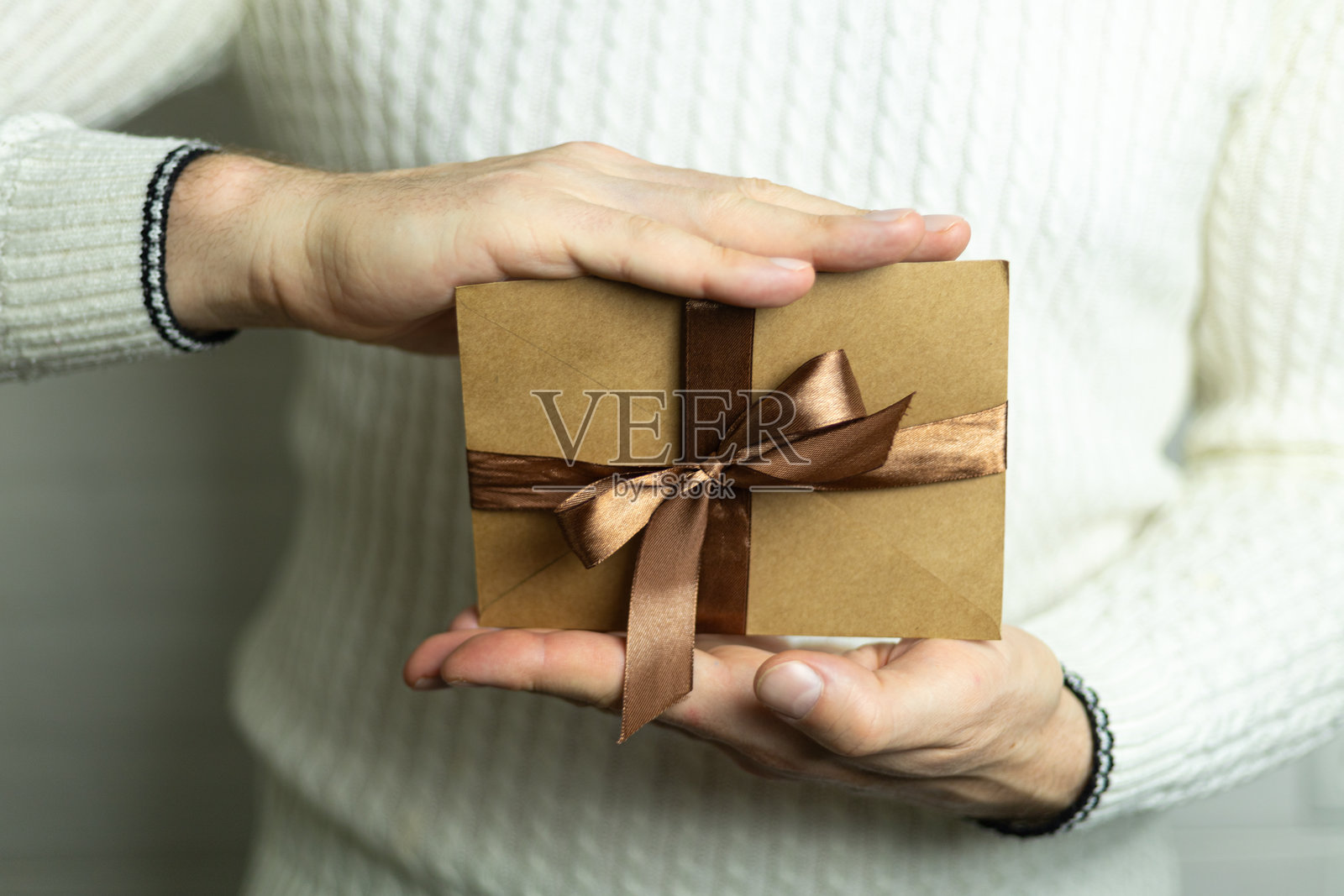 一个男人手里拿着一张系着棕色缎带的礼品券。照片摄影图片