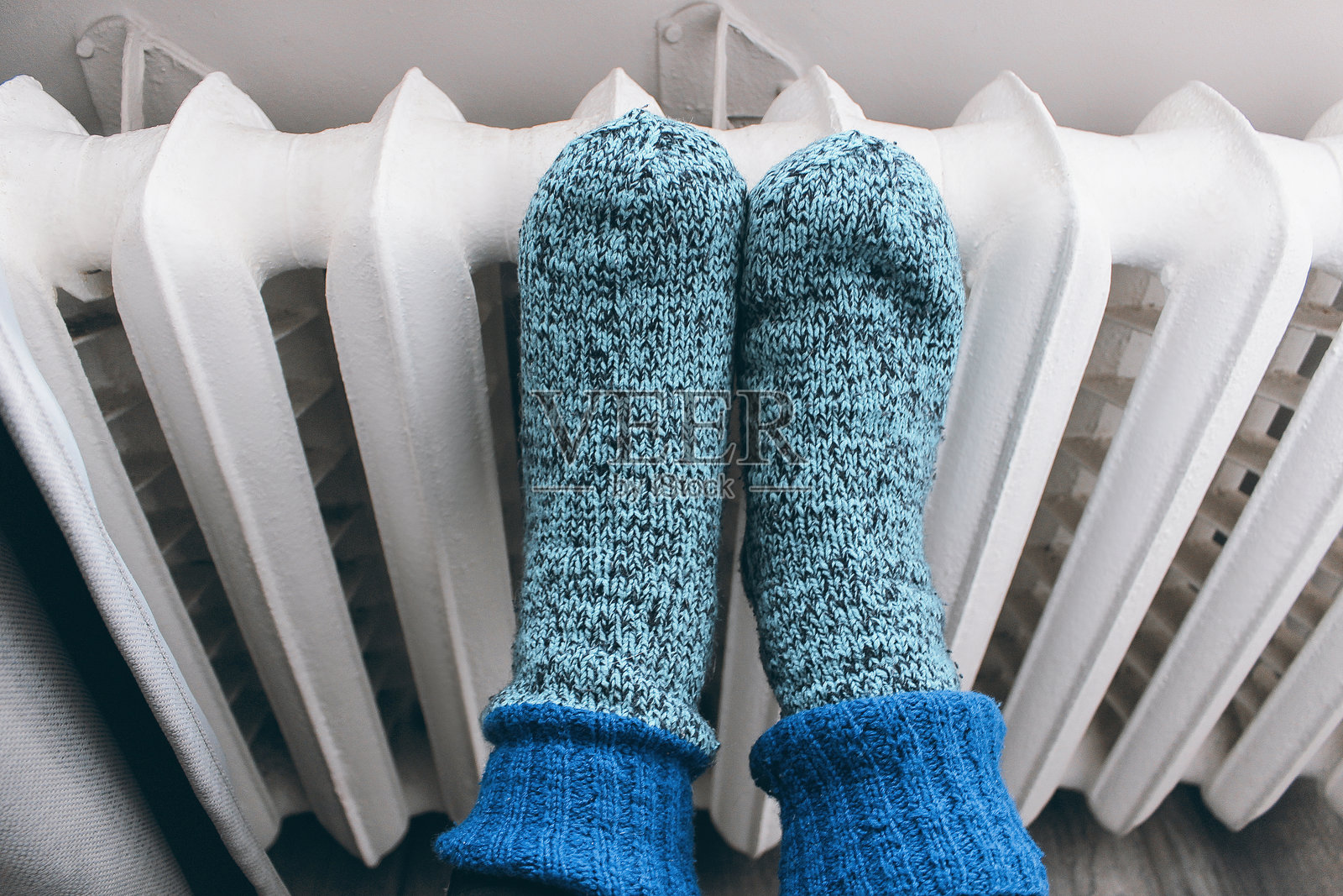 年轻女孩在寒冷的冬天，穿着温暖的毛线袜，靠近家里的取暖器。照片摄影图片