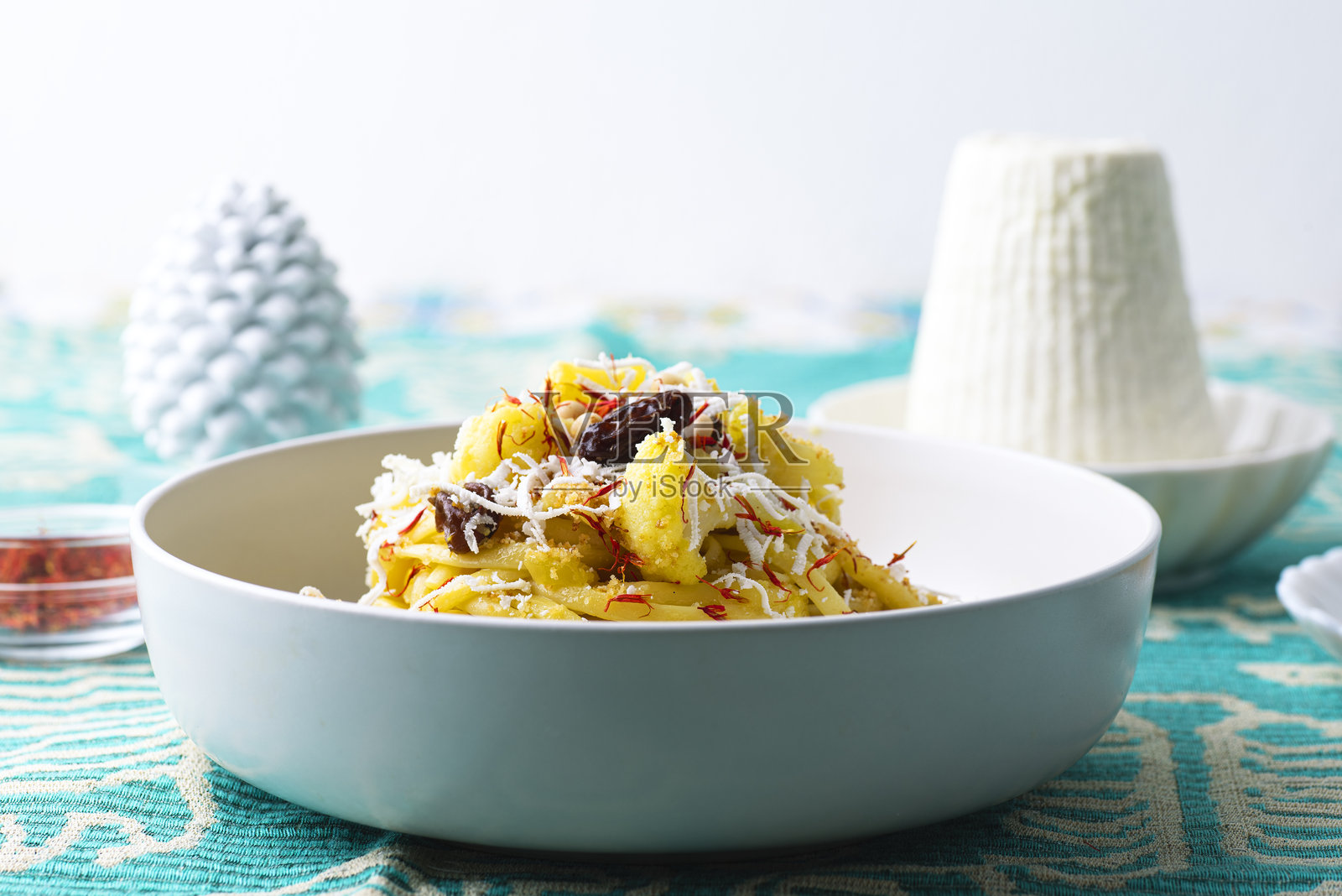 西西里花椰菜、葡萄干、藏红花、松子、咸凤尾鱼和面包丁的意大利面。搭配传统的里科塔沙拉奶酪。美丽而健康的西西里食谱。鲜艳的西西里民族风格。照片摄影图片