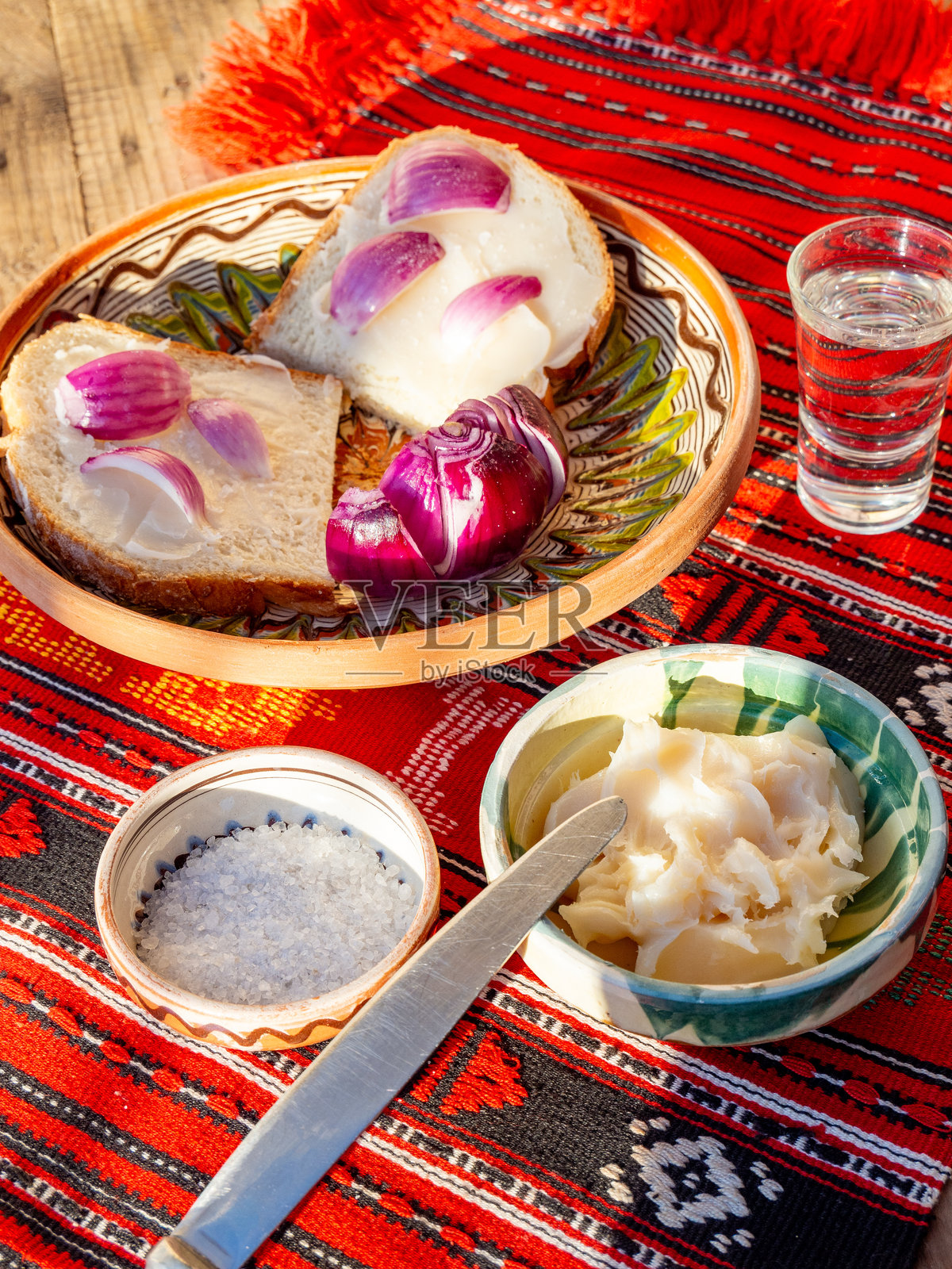 涂抹在面包上的猪油，配以红洋葱和盐，旁边是一杯梅子白兰地。照片摄影图片