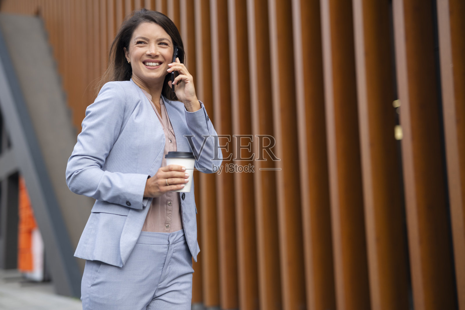 穿着西装的女商人在户外打电话。照片摄影图片