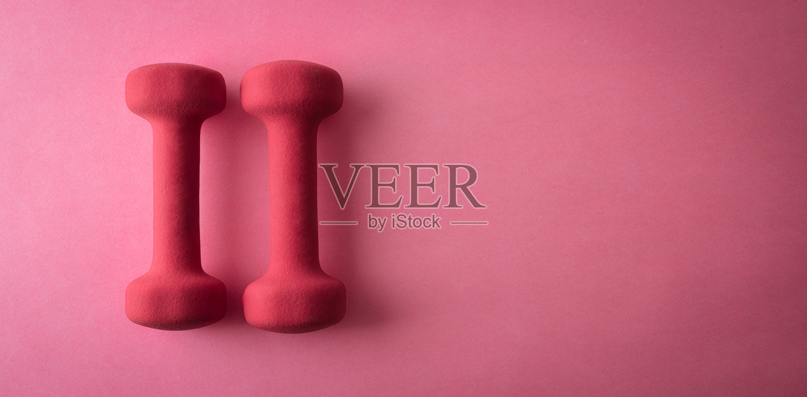 一组粉色氯丁橡胶哑铃，孤立在粉色背景上照片摄影图片