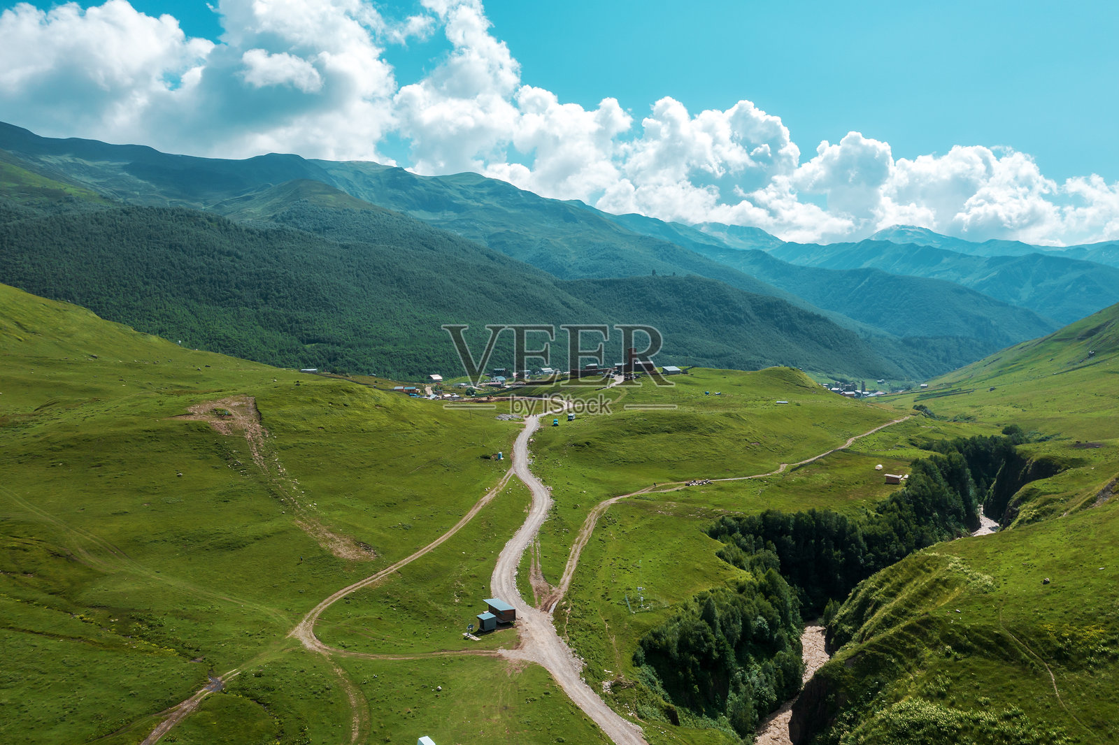 格鲁吉亚梅斯季亚的壮丽山脉地区，起伏的山丘、蜿蜒的小路和传统塔楼在明亮的天空下，唤起探索与宁静的感觉。照片摄影图片