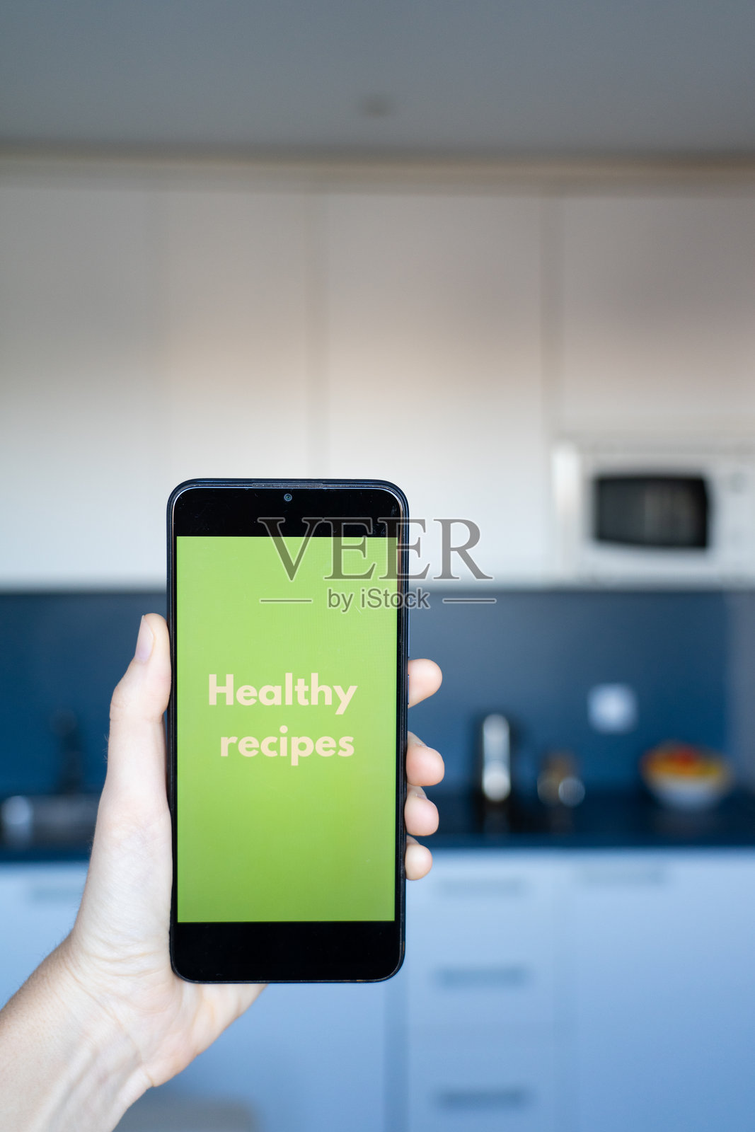 手握智能手机，在厨房中展示健康食谱应用程序照片摄影图片