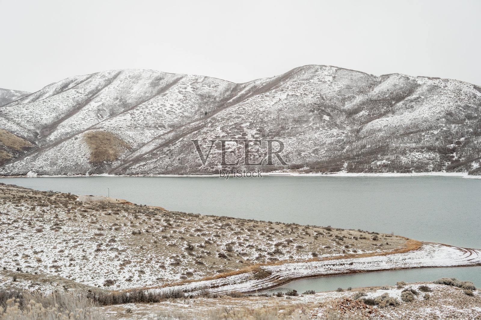 被雪覆盖的山丘和宁静湖泊，展现出犹他州山脉SLC峡谷的冬季宁静景观照片摄影图片