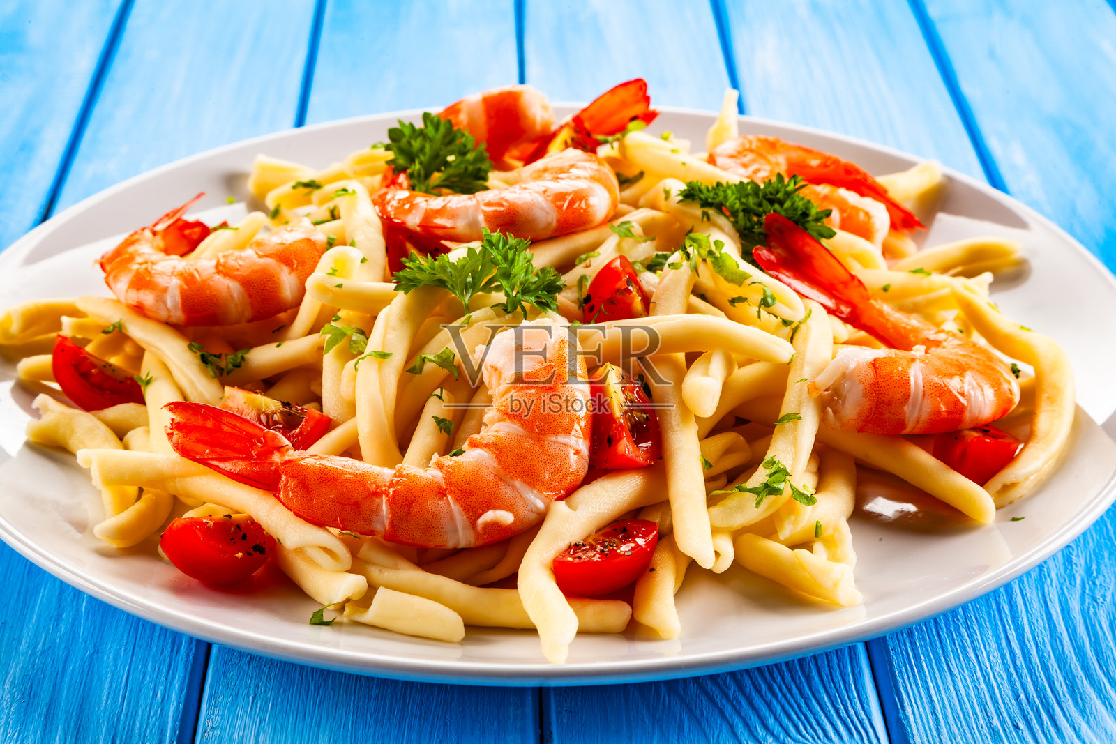 木桌上的虾仁意大利面、番茄和香菜照片摄影图片