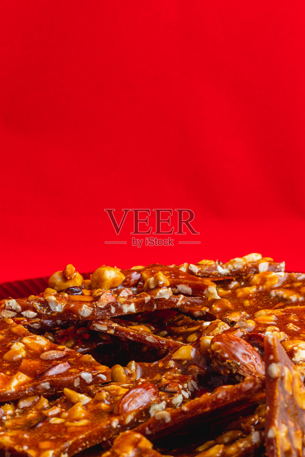 自制的糖饼干，上面撒有坚果，放在光亮的红色盘子上照片摄影图片