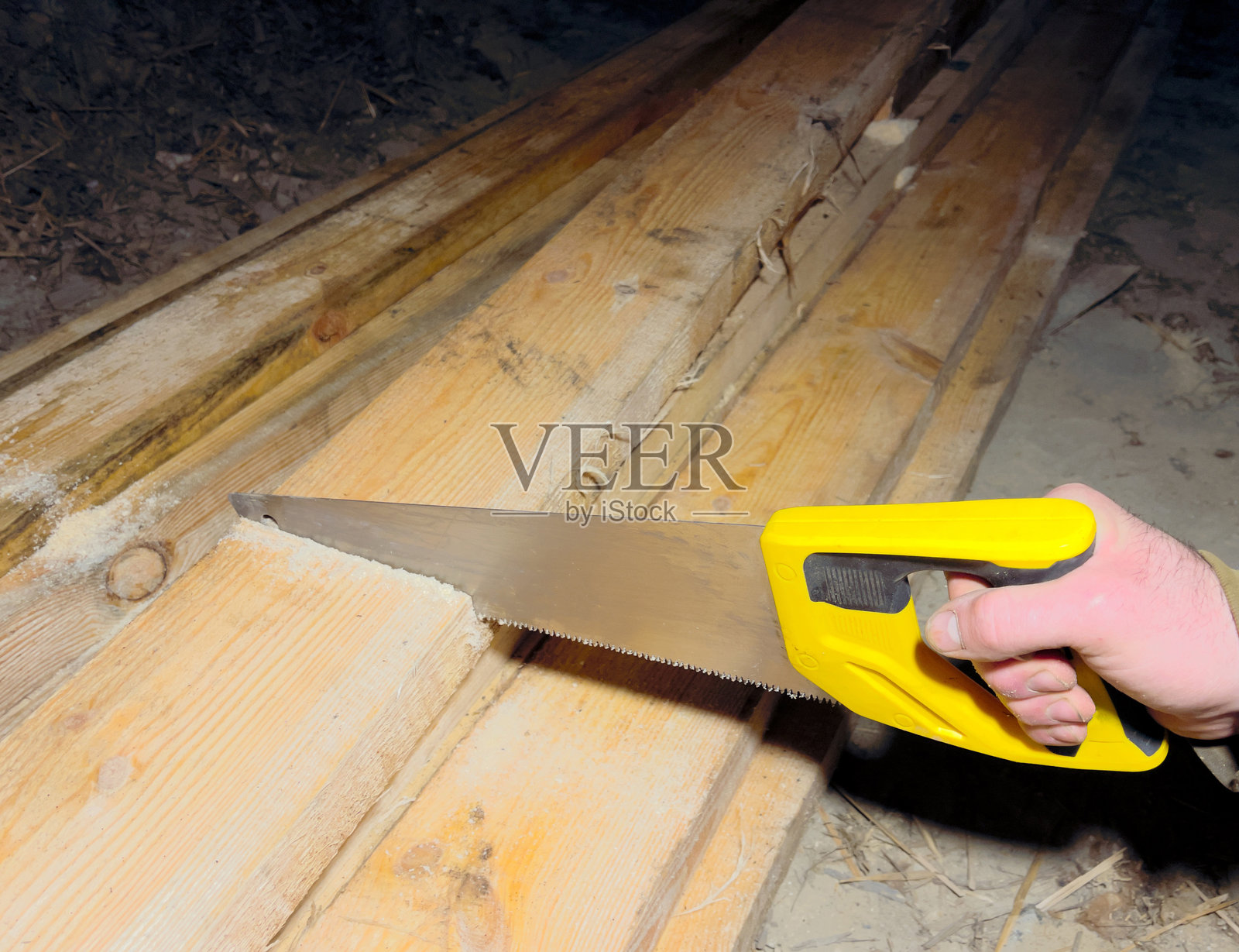 工匠的手握着锯子在树上。正在切割木梁。屋顶修理。照片摄影图片