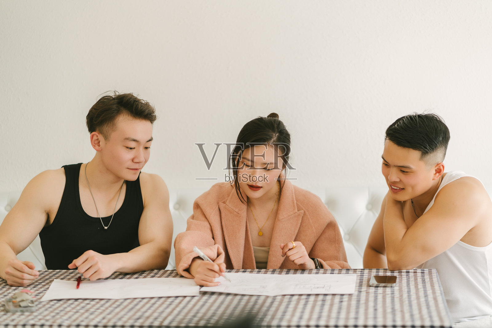 三位来自东亚的年轻人正在研究放在桌子上的蓝图照片摄影图片