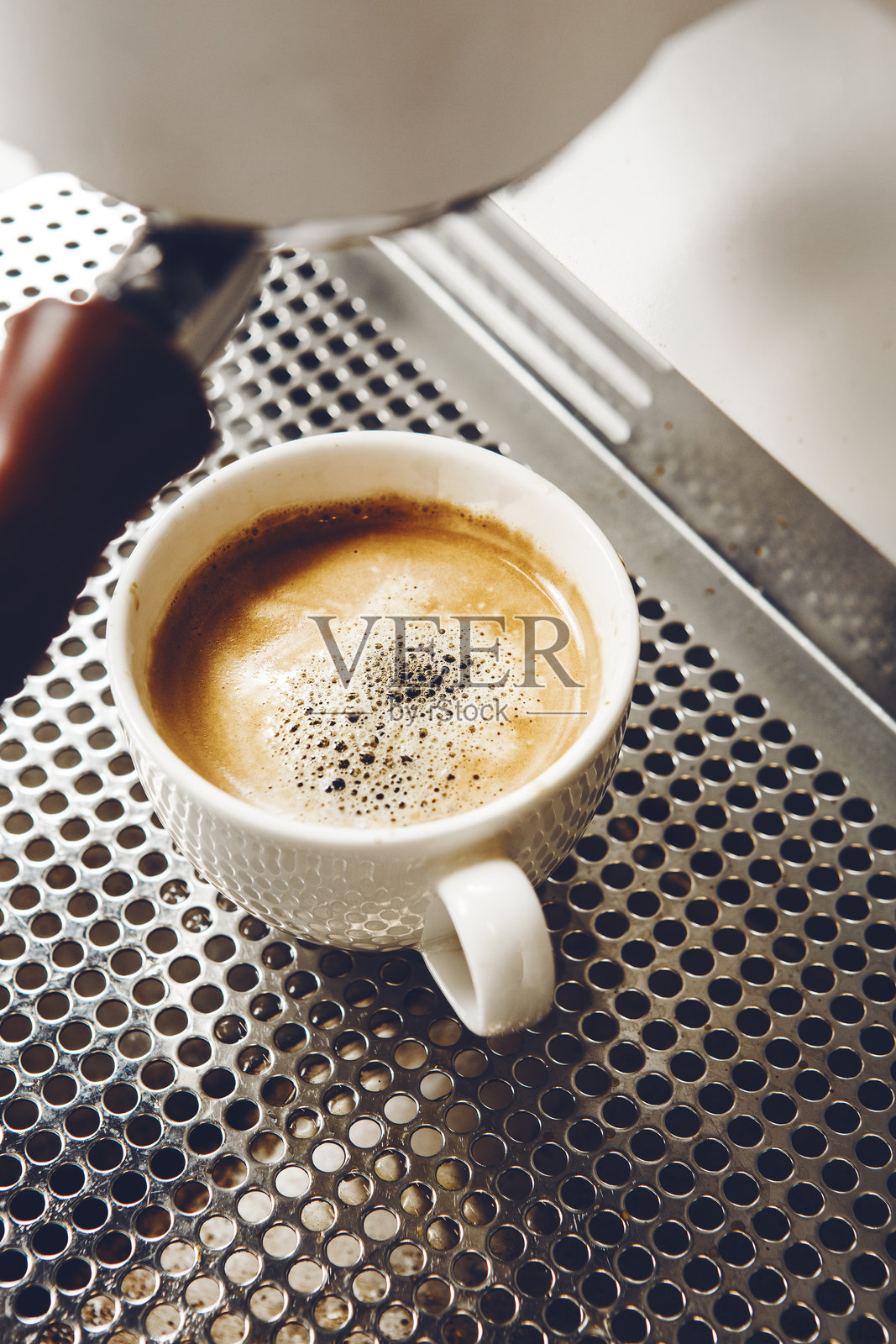 准备过程中，浓缩美式咖啡在咖啡机支架上溢出，特写镜头展示了这一瞬间。照片摄影图片