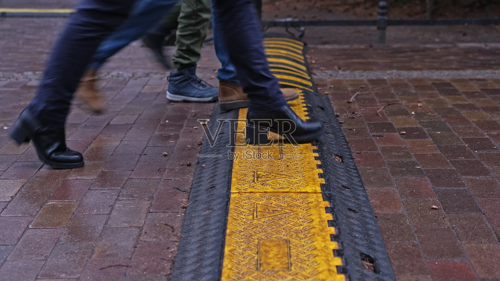 人们在公园小巷的人行道上走过户外黑黄相间的电缆保护器，保护电源线的安全。照片摄影图片