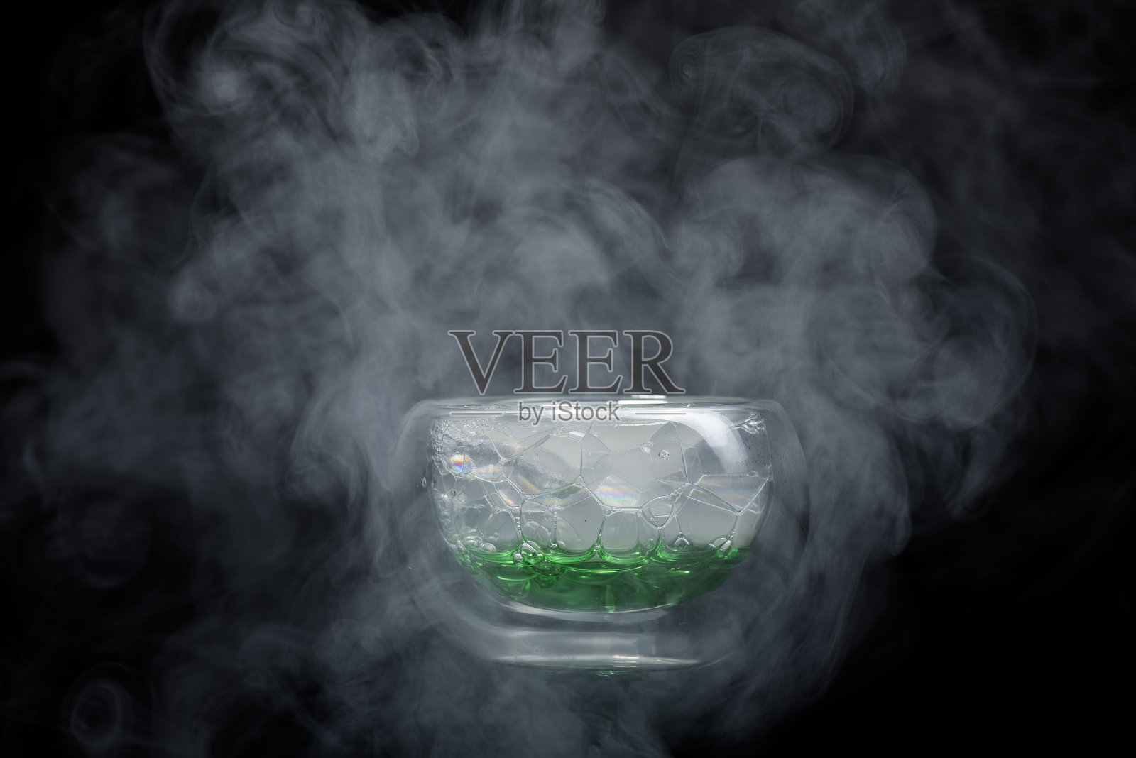 小玻璃碗，里面有气泡和旋转的烟雾与蒸汽云。照片摄影图片