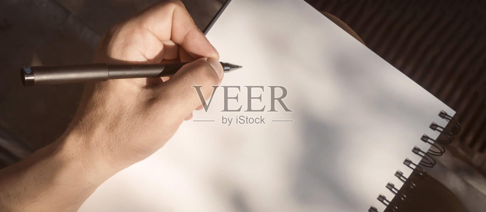 一个男人正在做笔记，手里拿着一本笔记本和一支笔。照片摄影图片