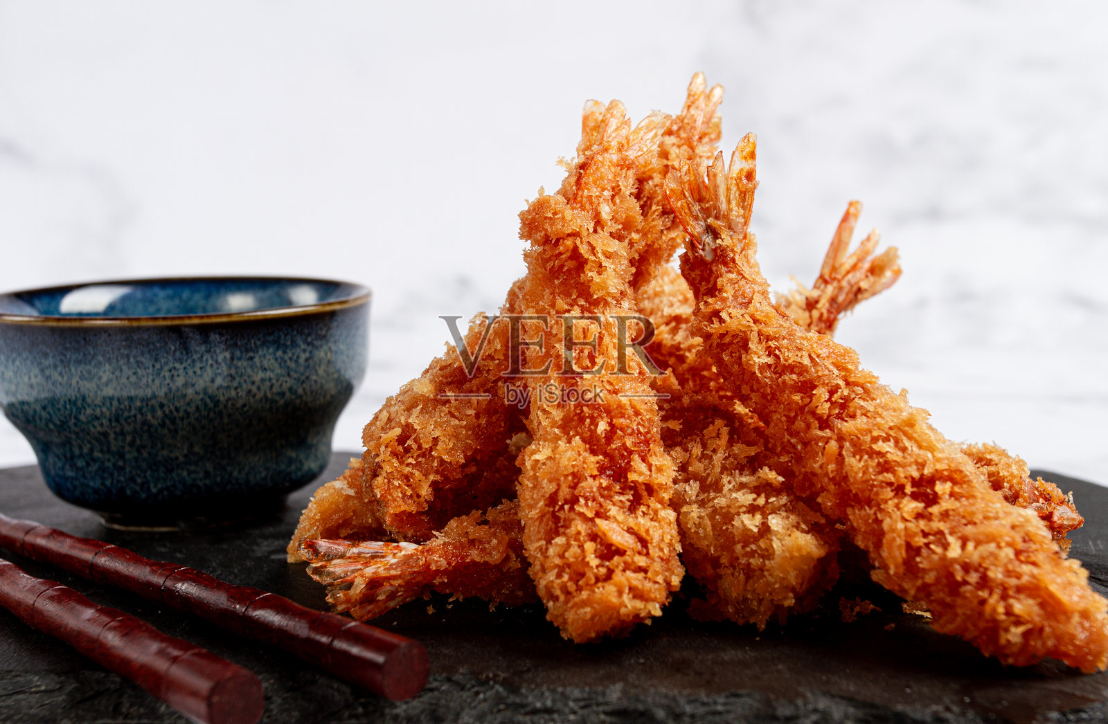 天妇罗虾，油炸，放在黑色石板上，配有酱汁，轻质大理石桌面，无人。照片摄影图片