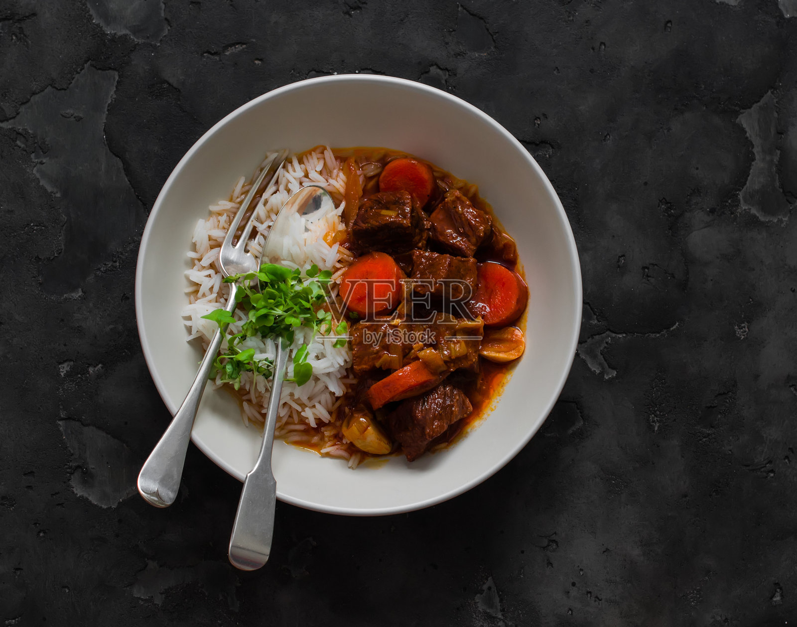米饭和炖牛肉配蔬菜 - 美味的舒适食品，黑色背景上的俯视图照片摄影图片