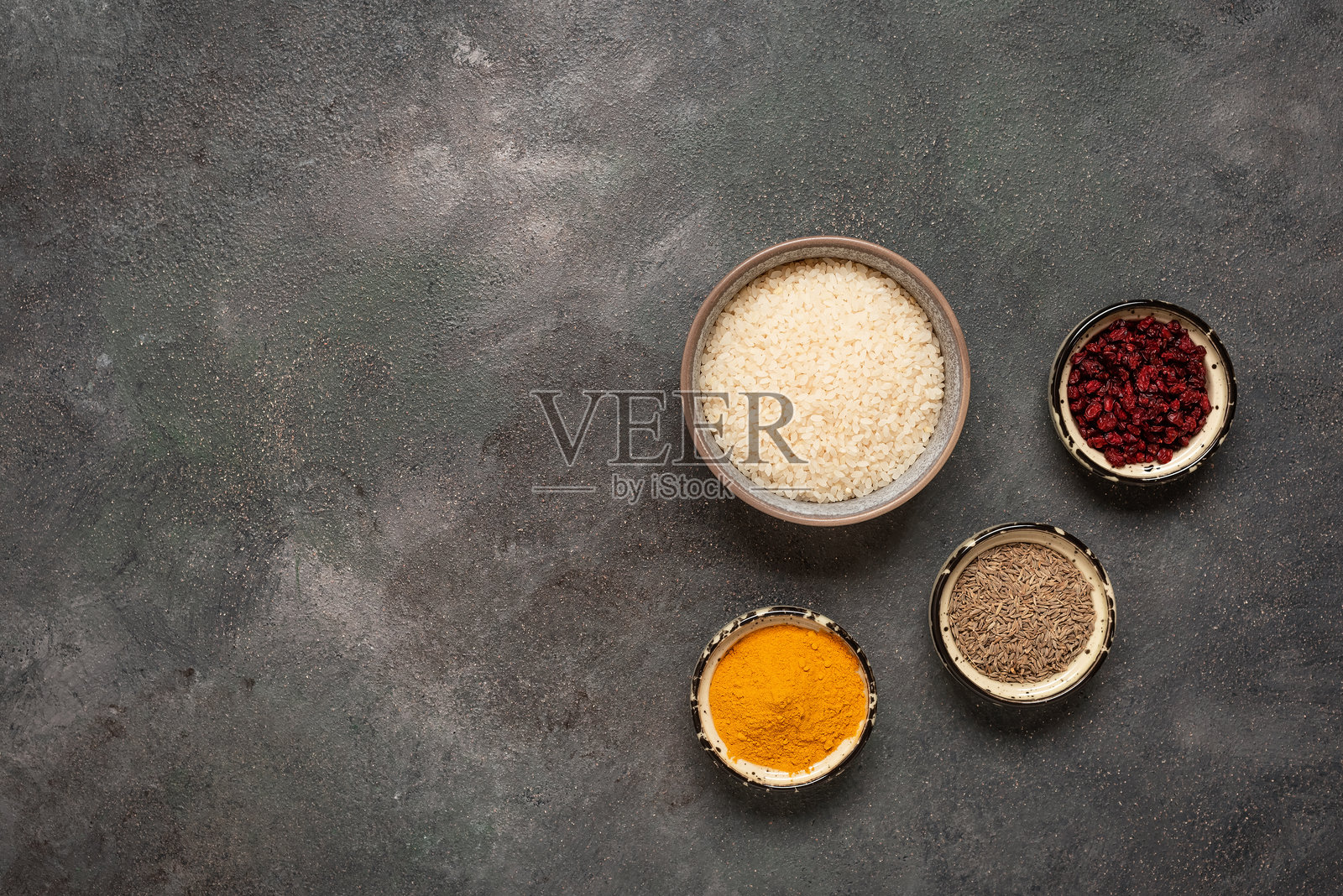 碗中的生米和用于烩饭的香料，孜然、姜黄、红果。俯视图，留白空间照片摄影图片