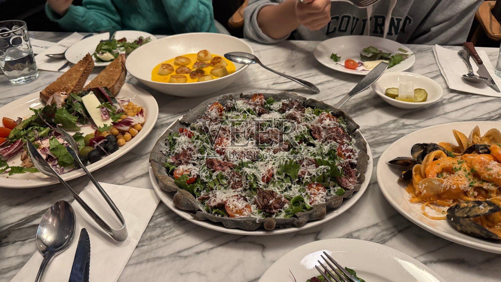 意大利经典美食的美妙组合——海鲜意面、香浓炭火披萨、丝滑的土豆饺子和色彩鲜艳的沙拉照片摄影图片