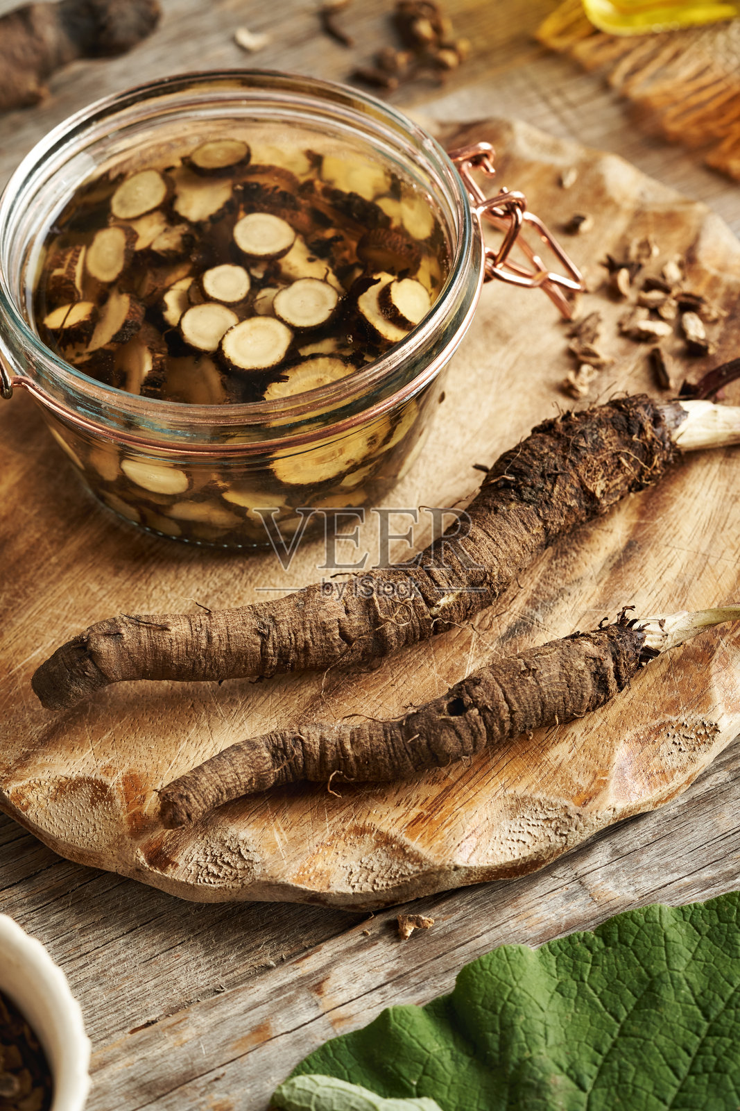 用玻璃罐准备新鲜野生牛蒡根和酒精的草药酊剂照片摄影图片
