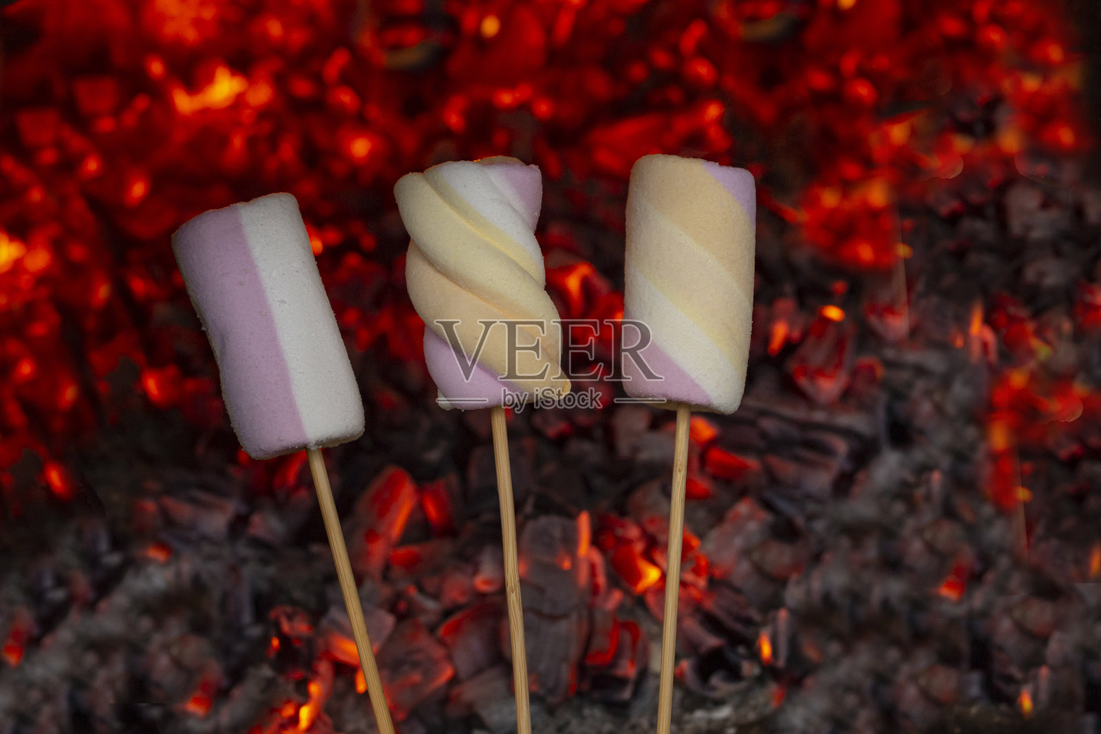 三根木签上的三个棉花糖，背景是红色燃烧的煤炭，柔焦特写照片摄影图片