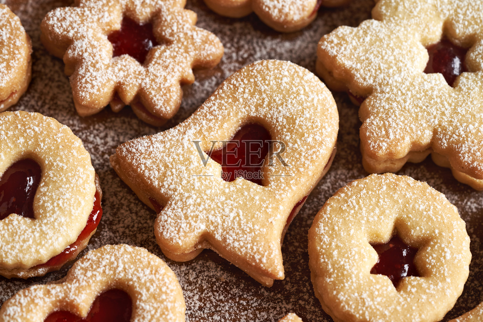 铃铛形的林泽尔圣诞饼干，夹有草莓果酱，撒上糖粉。照片摄影图片