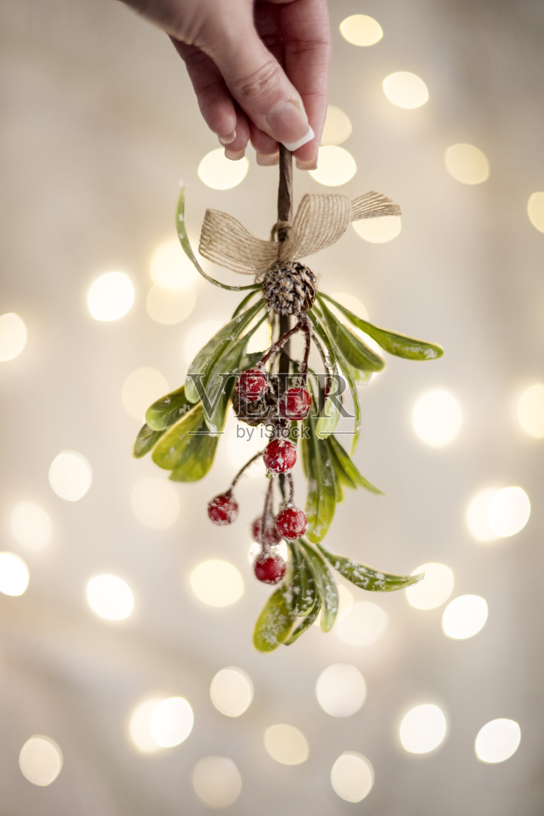 女人手持槲寄生与闪烁的灯光照片摄影图片