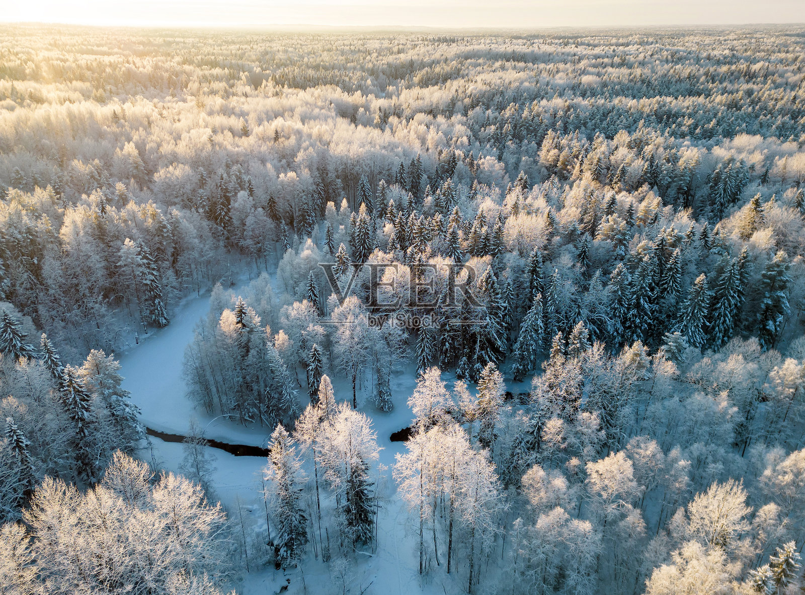 寒冬森林中的小河在日落时分。美丽的风景从空中拍摄。卡累利阿共和国。照片摄影图片