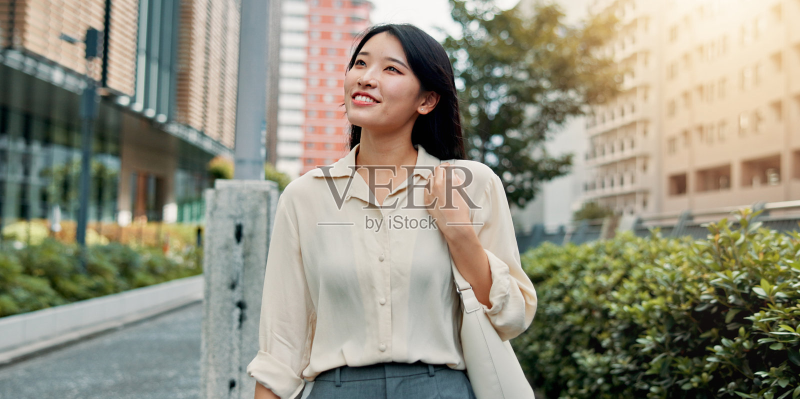 日本女性在城市中思考并散步，微笑并为旅行感到自豪。女性行人在街道上充满自信，享受作为游客的冒险经历。照片摄影图片