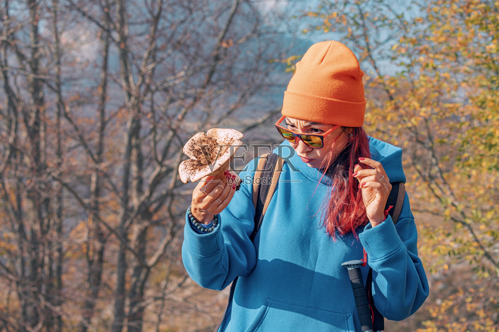 年轻女性徒步旅行者在秋季森林中手持蘑菇照片摄影图片