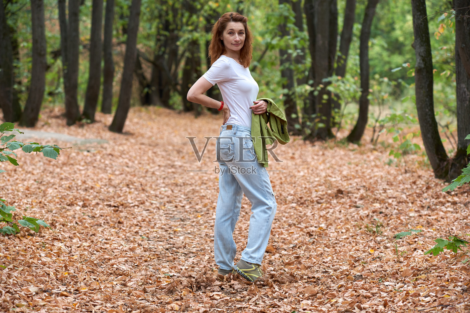 美丽的年轻女性在秋季森林中行走并看向镜头照片摄影图片