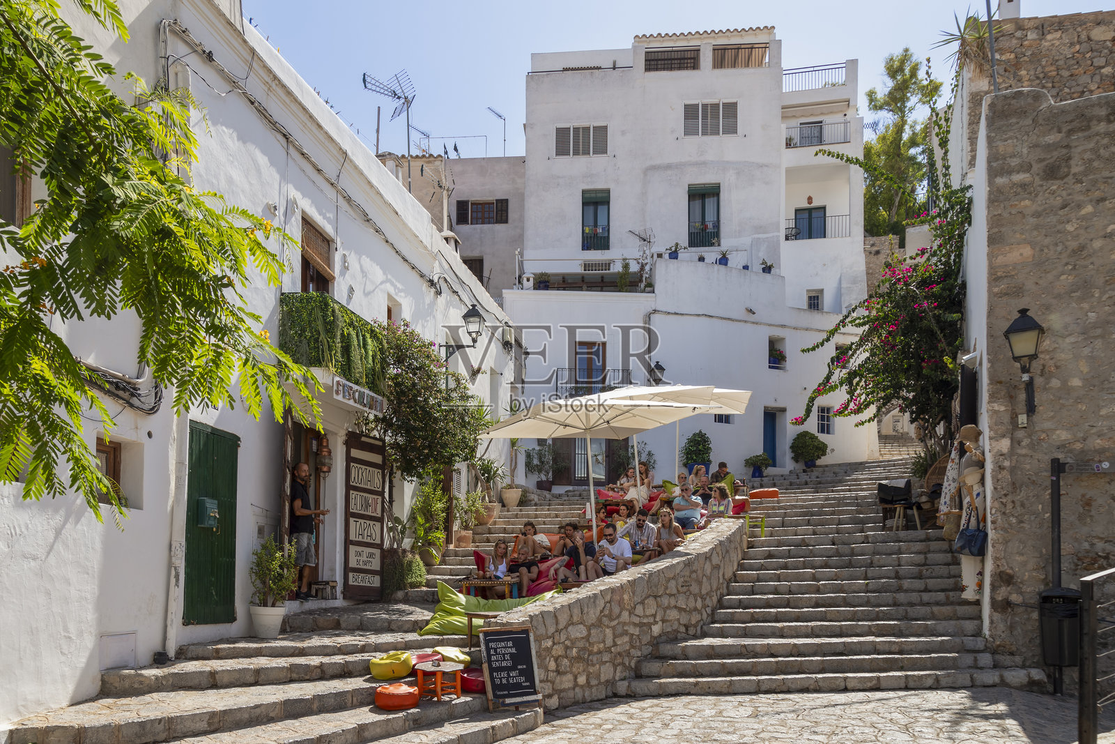 人们在伊比萨镇老城区的一家餐厅的石阶上享用饮品。照片摄影图片