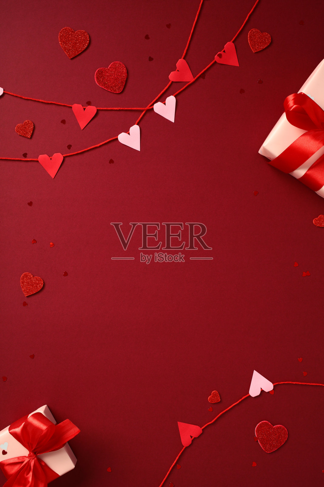 情人节背景，红色和粉色心形装饰花环，带红色丝带的礼品盒，以及红色背景上的心形彩纸屑。社交媒体故事横幅模板。照片摄影图片