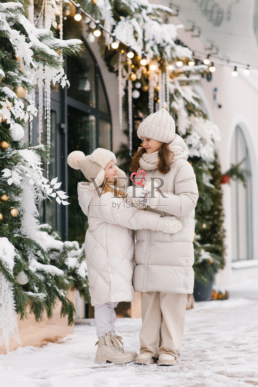 女孩们站在圣诞商店的橱窗前照片摄影图片