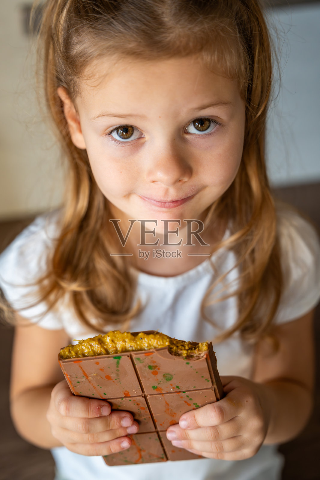 小女孩手中拿着含有开心果酱和卡塔伊菲面团的迪拜巧克力。在厨房里自制的手工糖果。照片摄影图片