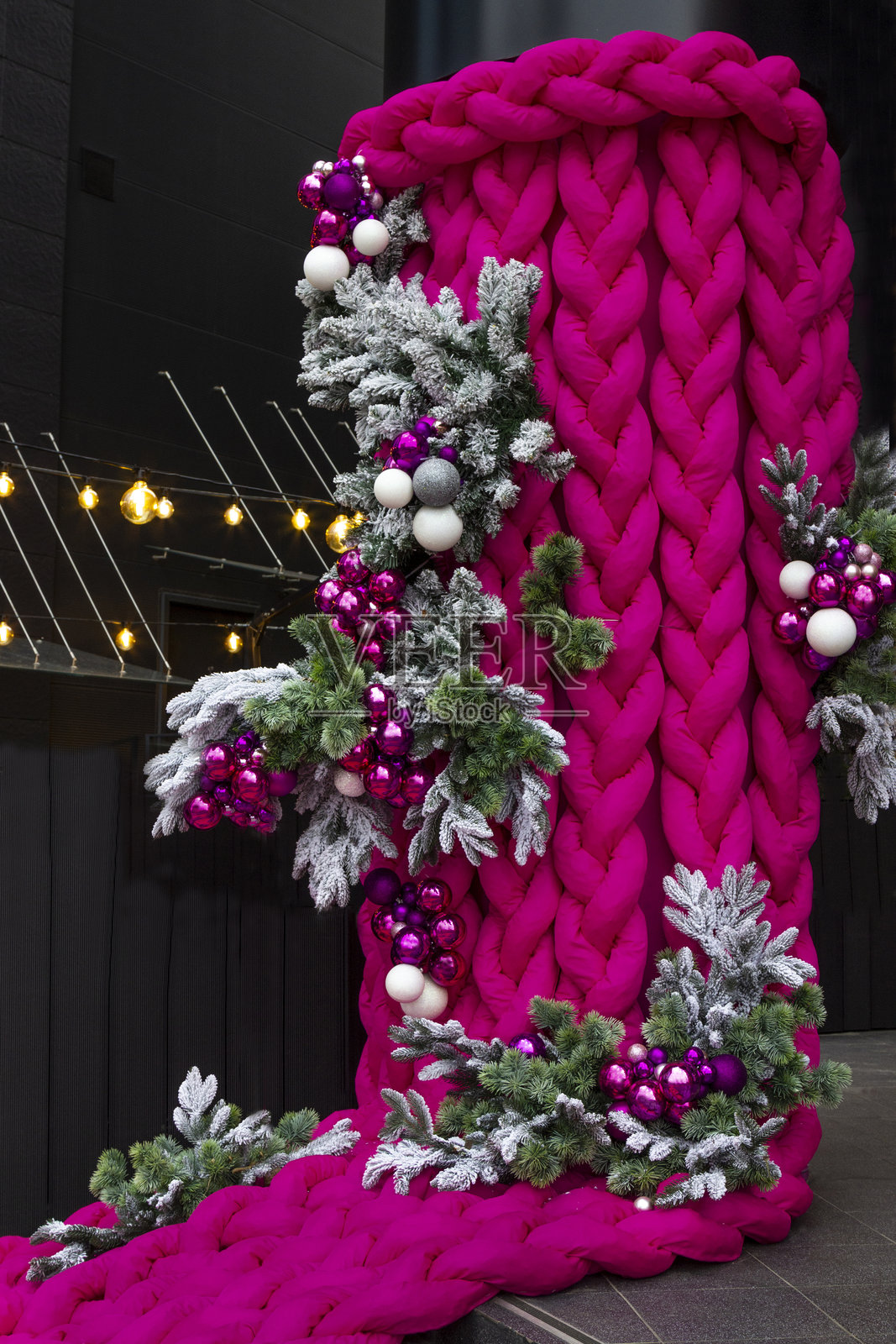 户外圣诞装饰。编织的粉色布条。松树枝和彩色球。照片摄影图片