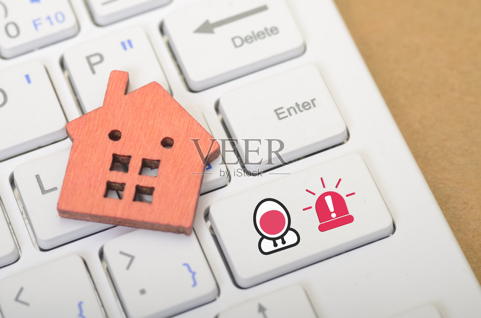 键盘上的房屋图标与警报符号的图像暗示了家庭安全的概念，以及保护个人财产和物品的重要性。保护财产免受诈骗者侵害：通过数字安全措施保护您的资产。照片摄影图片