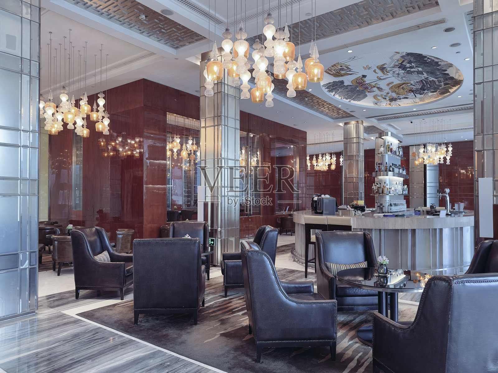 豪华酒店休息区，配有优雅的皮革扶手椅、中央圆桌和精致的照明设计，装饰有华丽的吊灯。照片摄影图片
