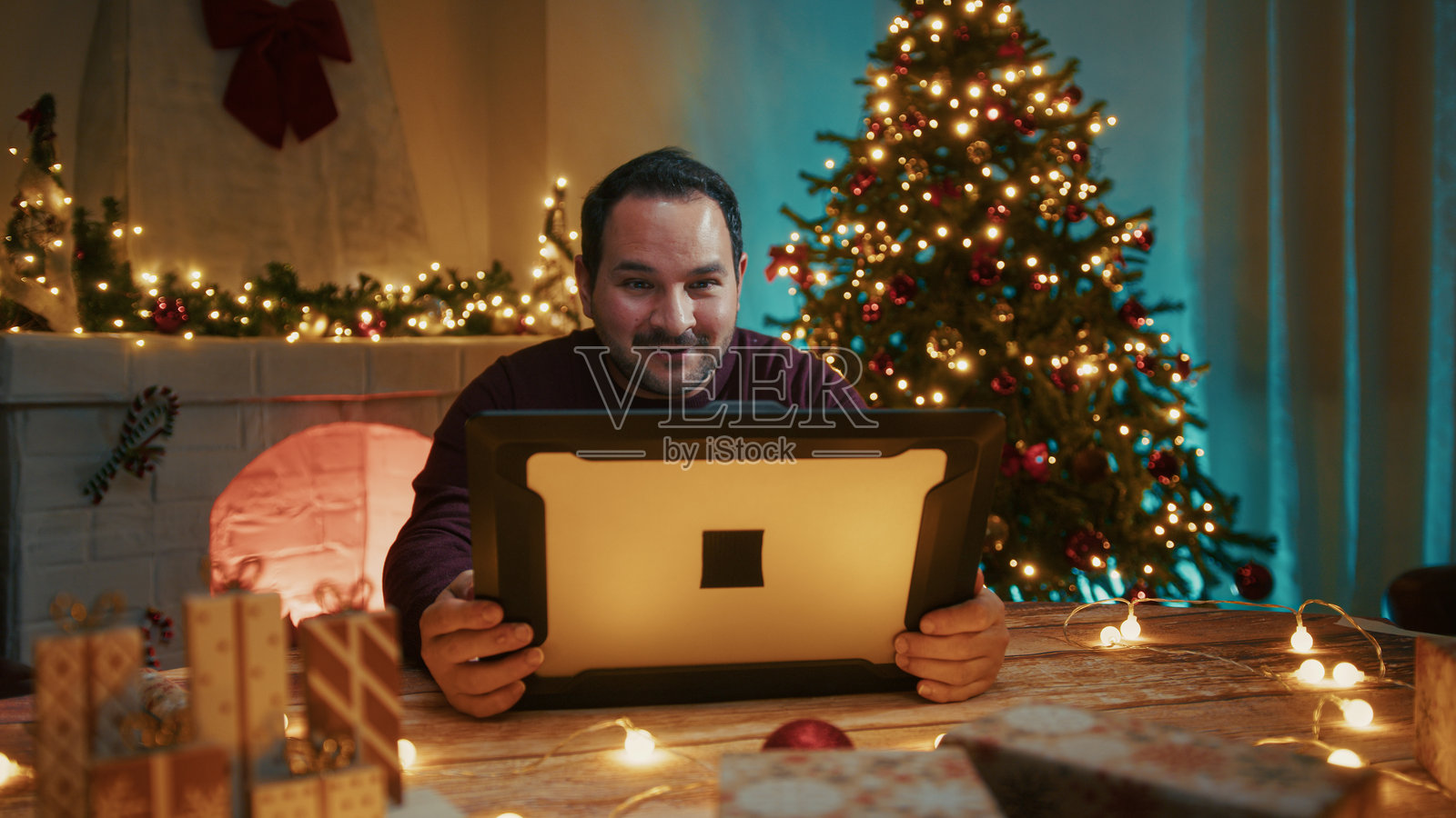 男人在装饰有圣诞节装饰的房间里用电脑进行视频通话照片摄影图片
