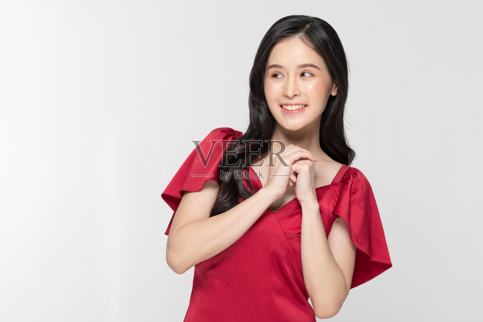 穿着红色裙子的梦幻年轻女性，带着希望的表情望向一旁，白色摄影棚背景照片摄影图片