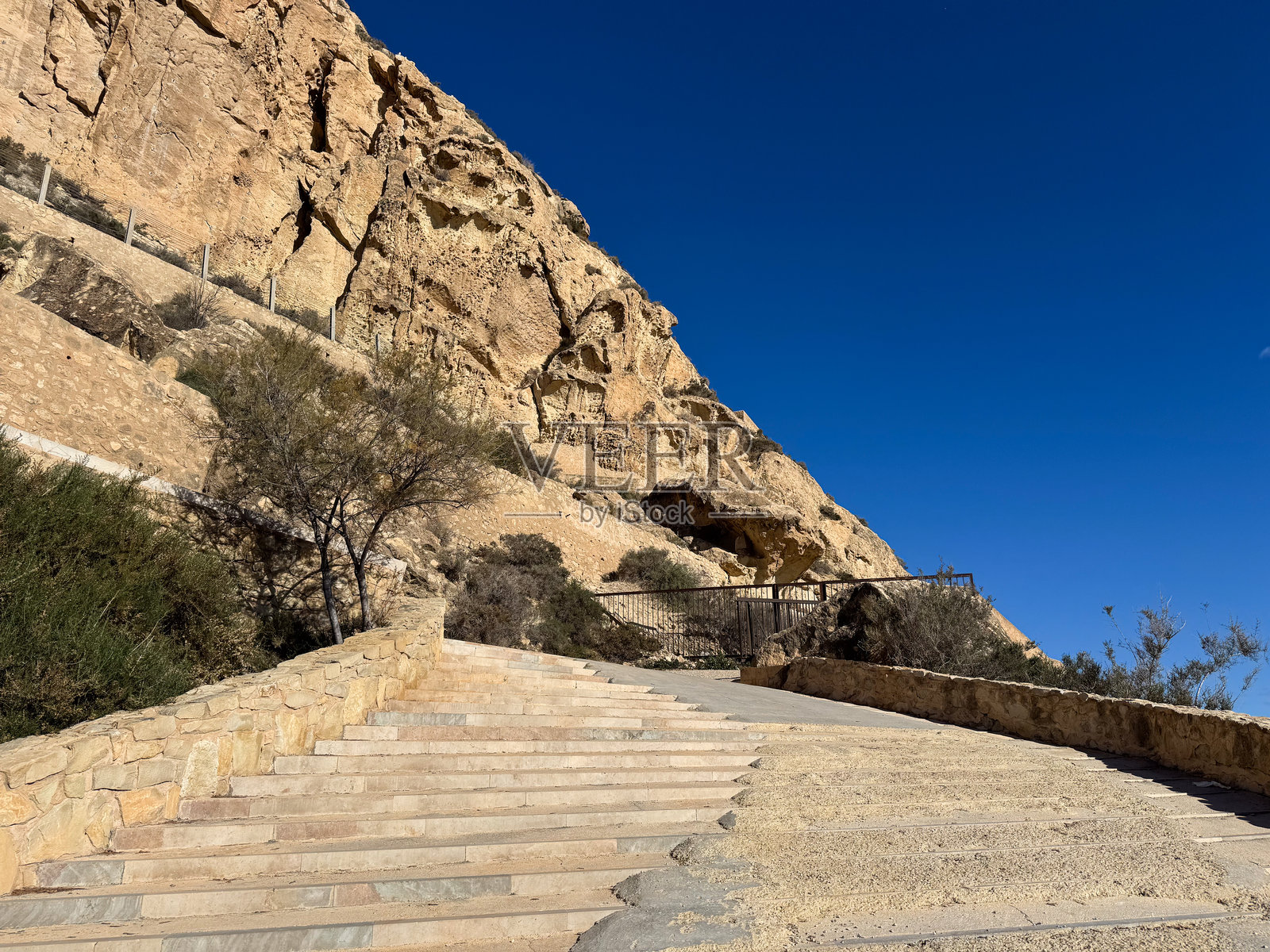 风景如画的沙漠小径通向岩石山脉，蓝天晴朗照片摄影图片