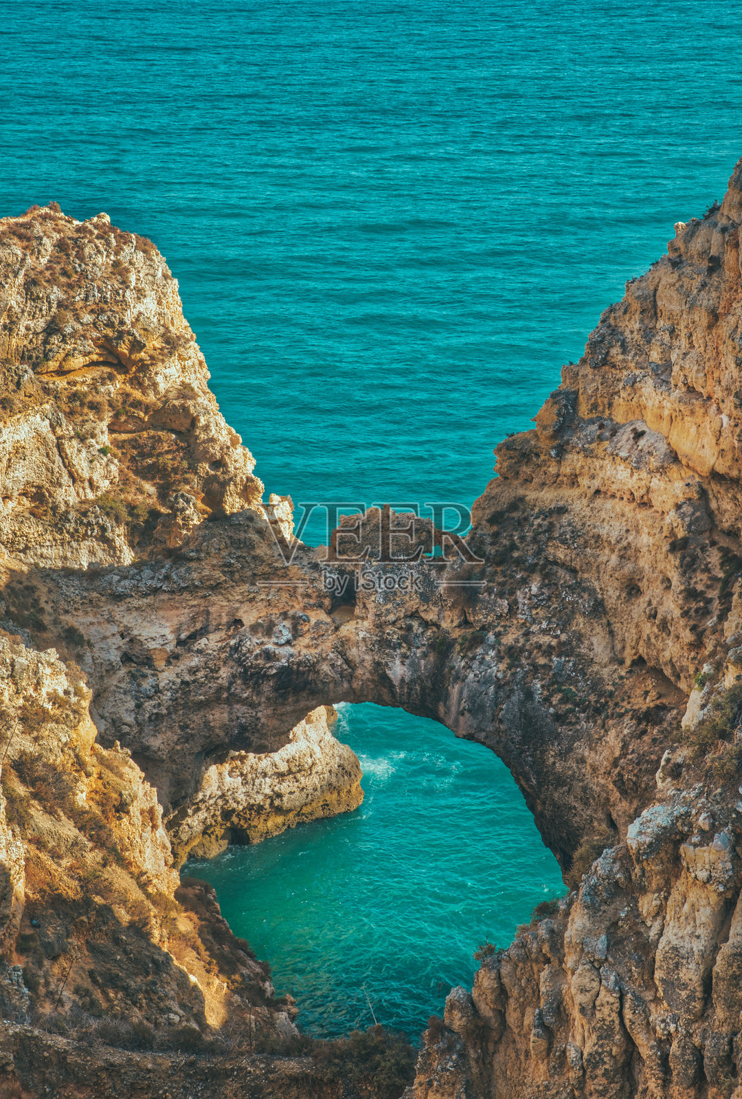 葡萄牙拉各斯的庞塔达皮达德岩石形成环绕着碧蓝的海水照片摄影图片