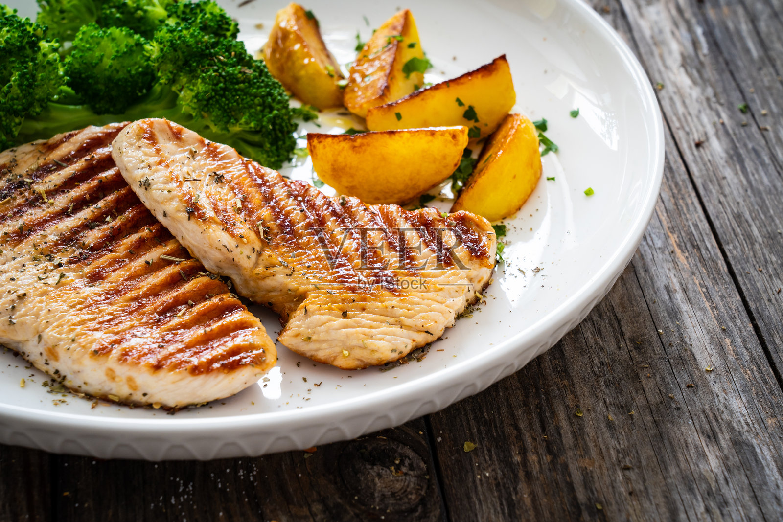 木桌上的烤火鸡胸肉和西兰花照片摄影图片