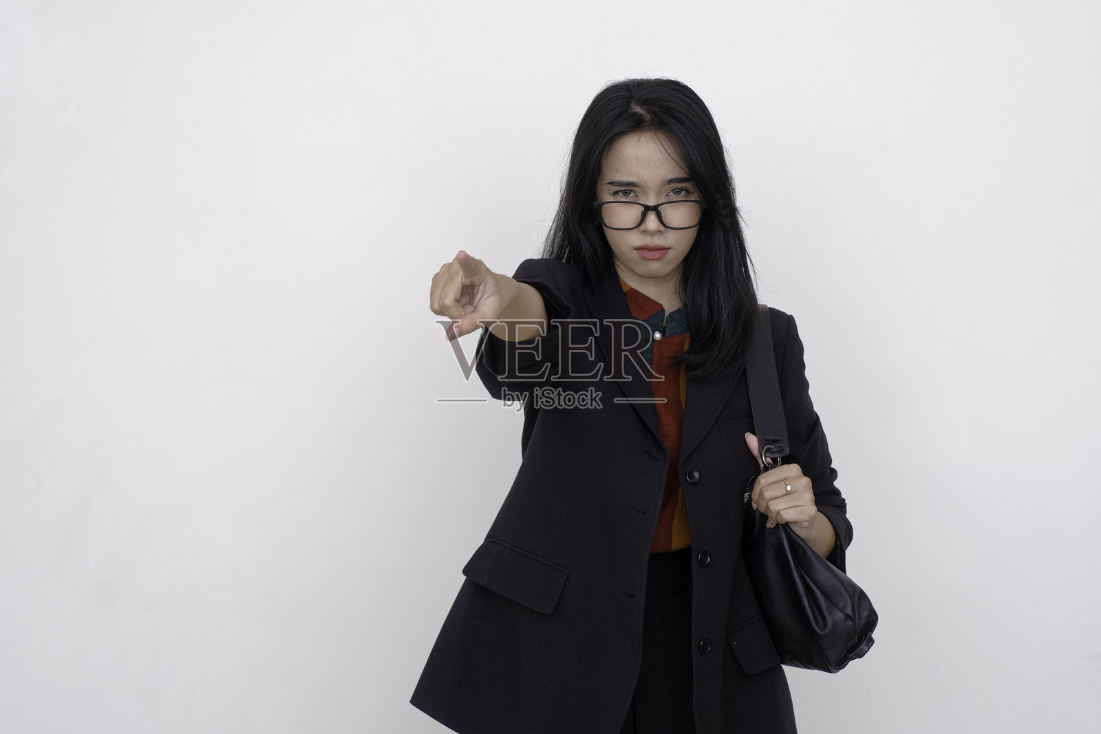 亚洲女商人站着，用食指指向某人，面无表情。照片摄影图片