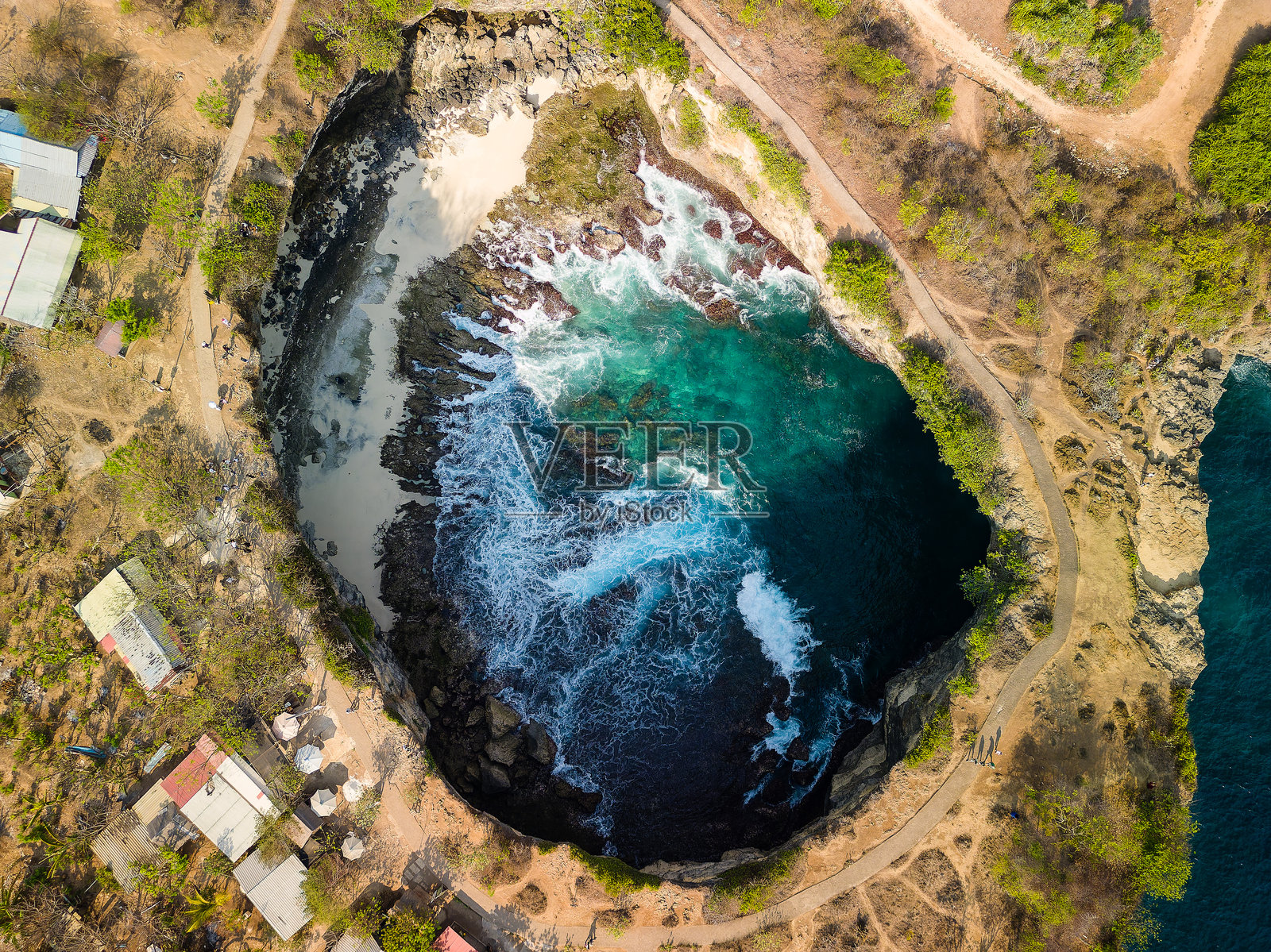 海洋波浪和一个位于天坑内的小海滩的无人机拍摄（破碎海滩，努沙佩尼达）照片摄影图片