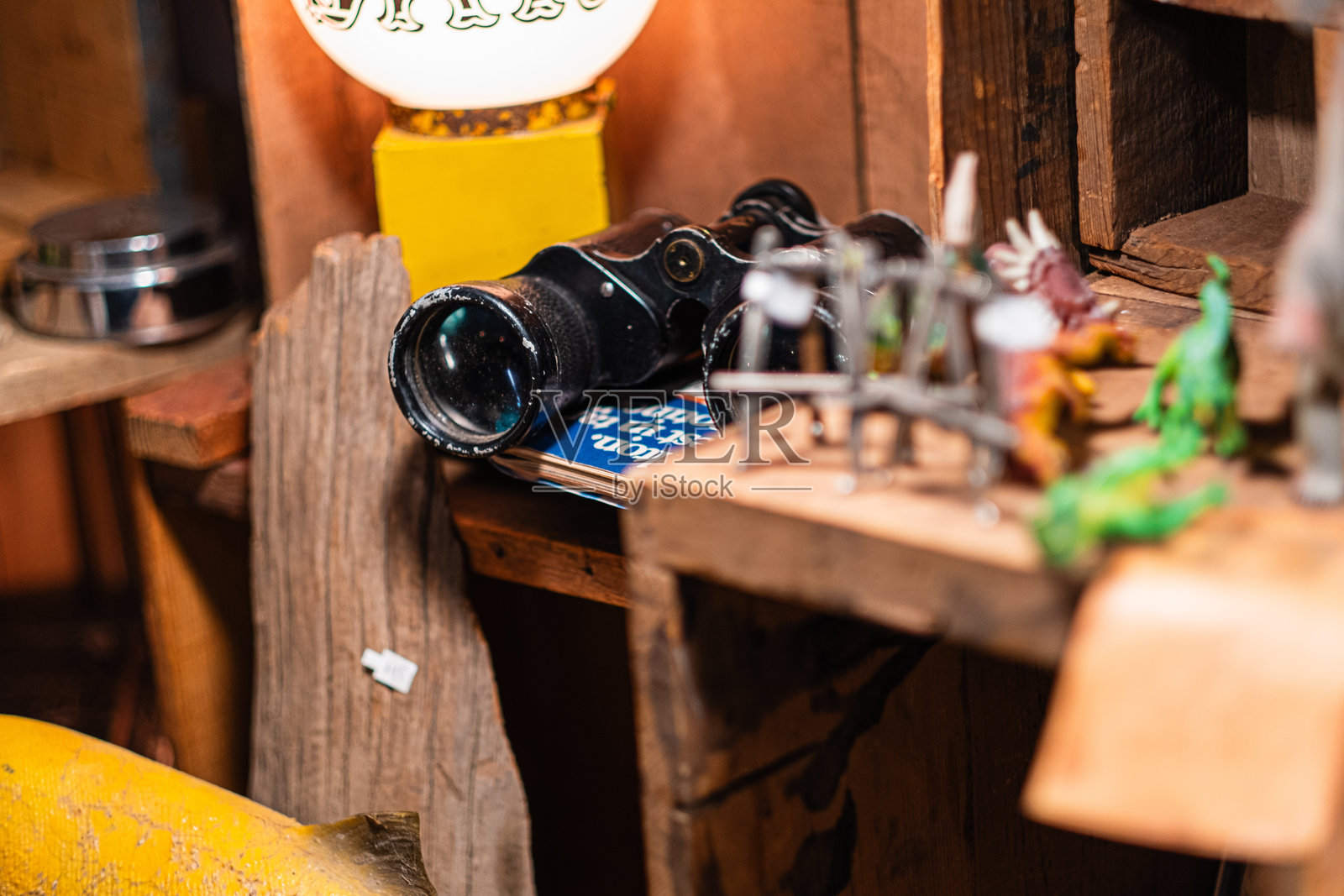 复古静物，旧望远镜和各种模型恐龙摆放在温暖环境光下的粗糙木架上照片摄影图片