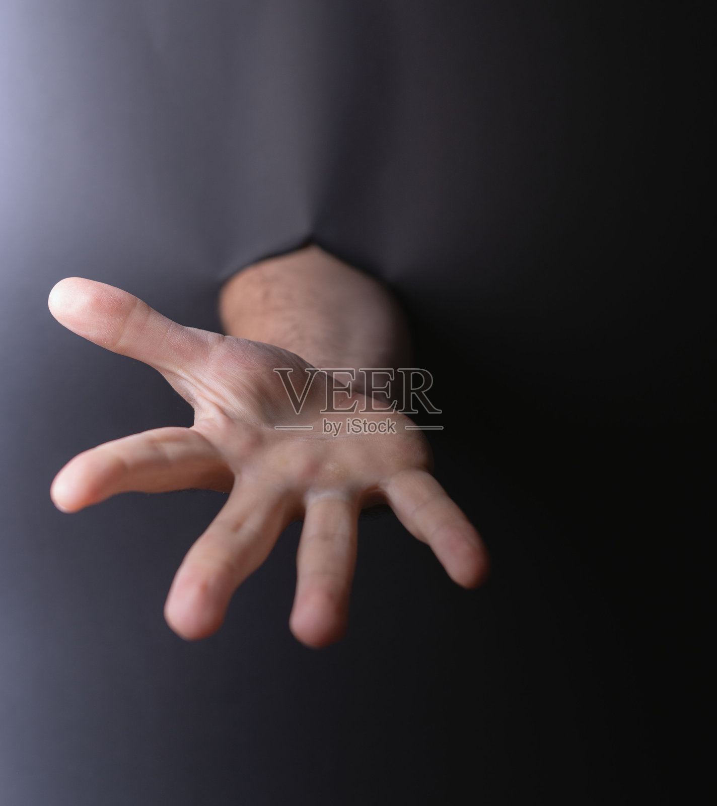 细致而富有表现力的人手从阴影中伸出，唤起神秘、邀请以及人类联系与触及的象征主题。照片摄影图片