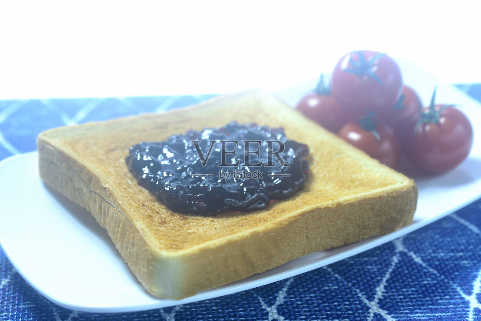 烤面包、蓝莓果酱和樱桃番茄在盘子上照片摄影图片