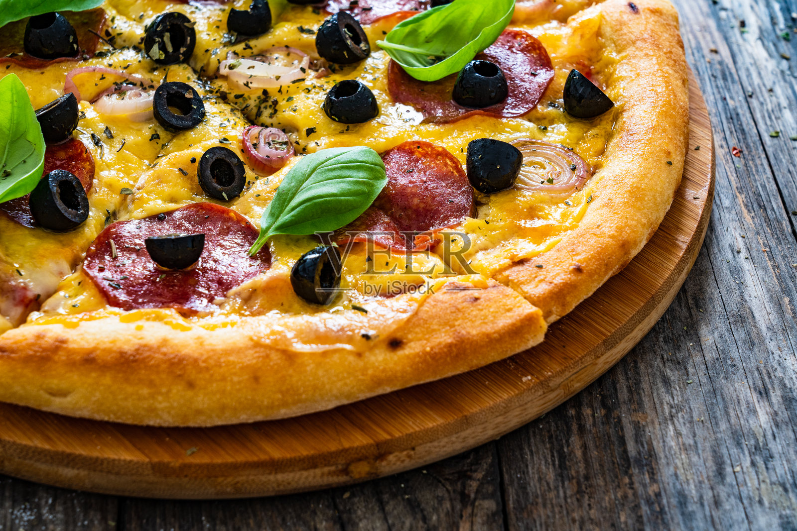 圆形意大利香肠披萨，上面有马苏里拉奶酪和黑橄榄，背景为木质纹理照片摄影图片